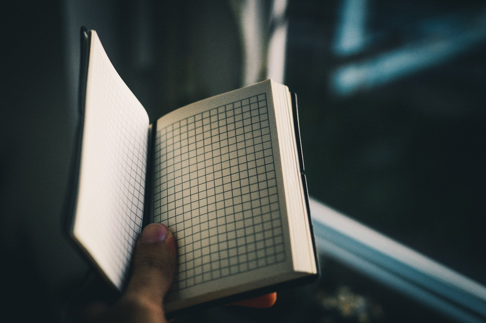 a hand holding open a graph paper notebook