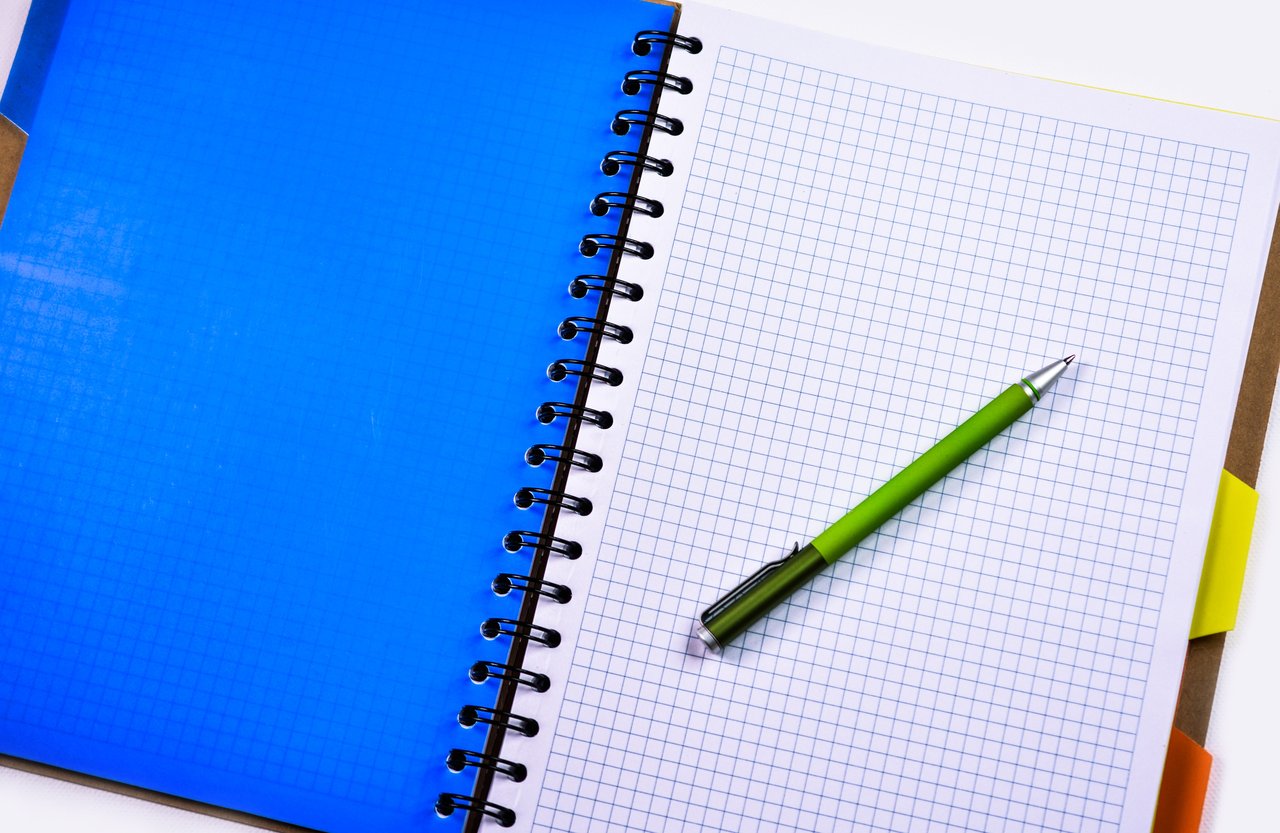 a pen resting on a graph paper notebook